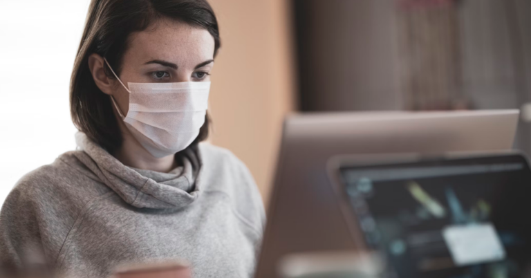 woman in gray hoodie wearing white face mask