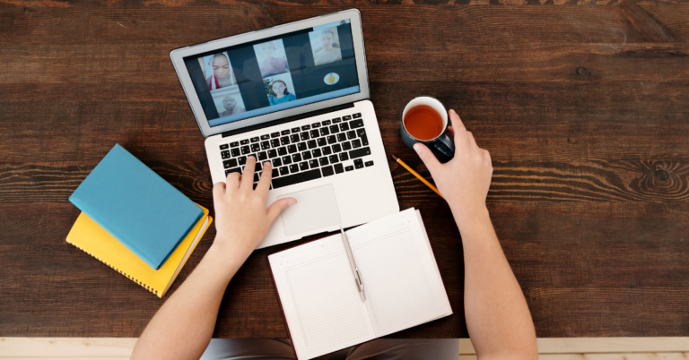 person attending a virtual meeting with a drink and their stationary by them